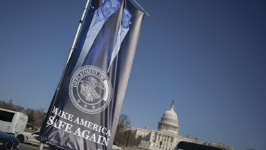 A banner of a photograph of Donald Trump and Jeffrey Epstein, emblazoned with the phrase, "Make America Safe Again," stands in front of the Capitol