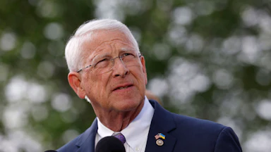 Senator Roger Wicker stands in front of two mics