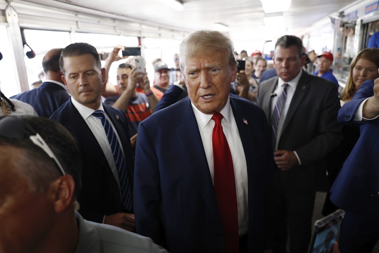 Donald Trump looks speaks, brows furrowed, as a crowd surrounds him.