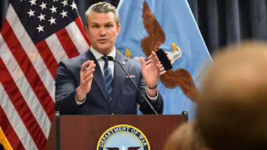 Defense Secretary Pete Hegseth gestures while speaking at a podium labeled "Department of War"
