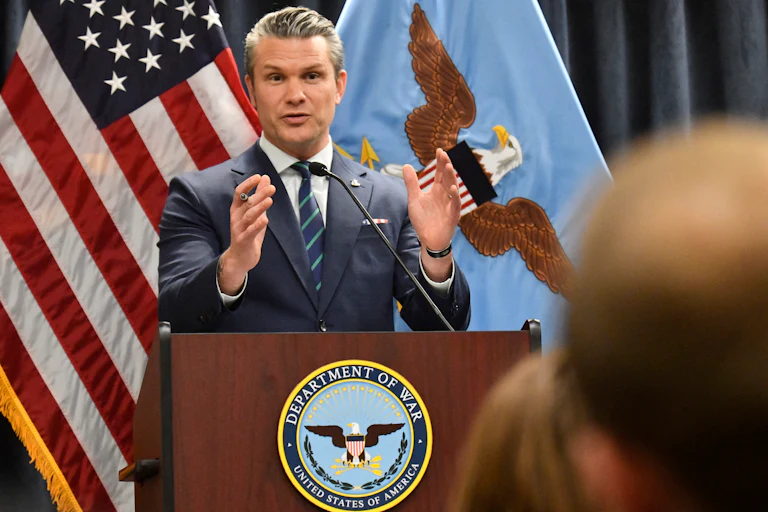 Defense Secretary Pete Hegseth gestures while speaking at a podium labeled "Department of War"