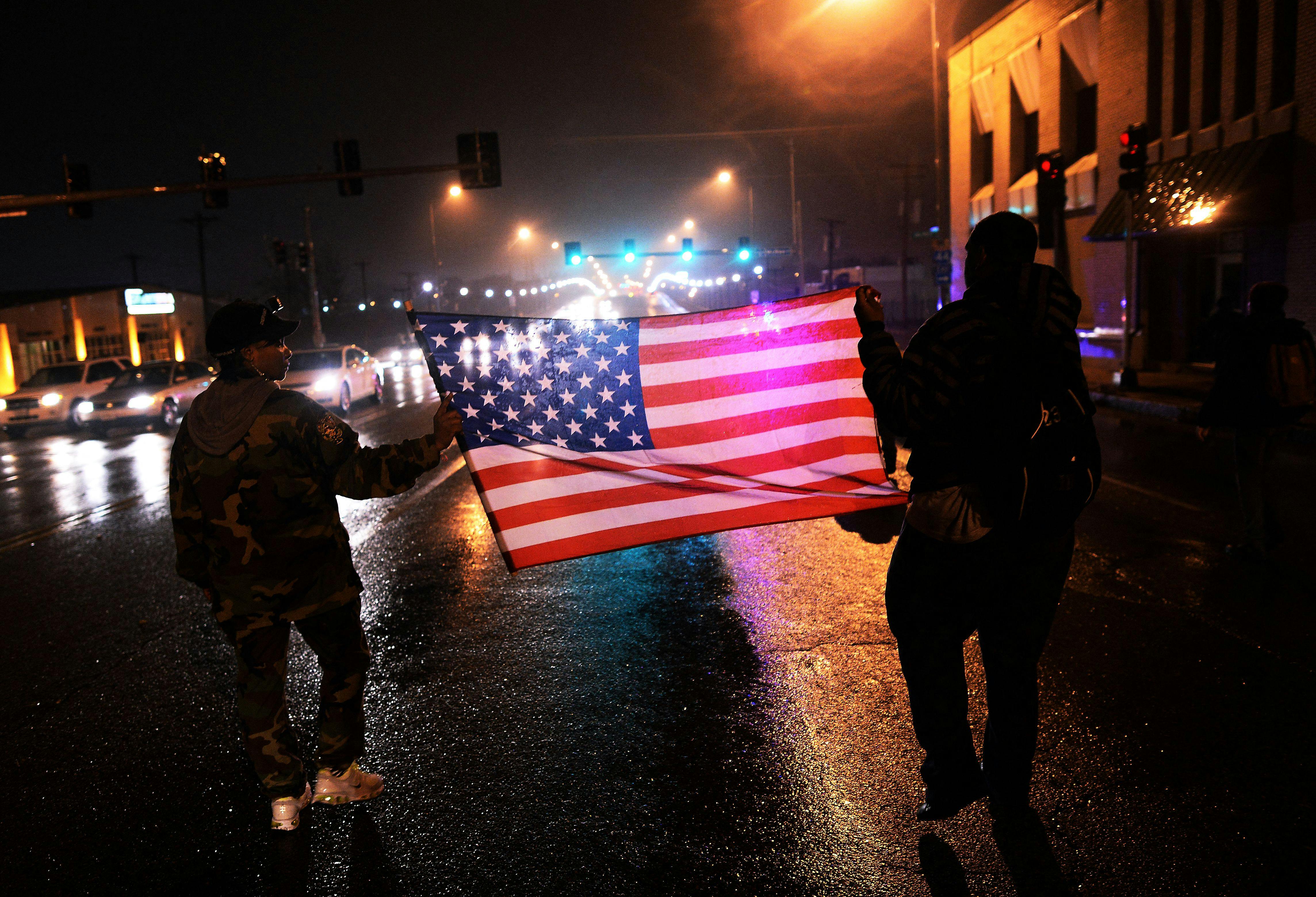 Demonstrators march with an American flag in St. Louis, Missouri, in November 2014 to protest the death of Michael Brown, an unarmed Black teenager who had been shot by police earlier in the year in nearby Ferguson.