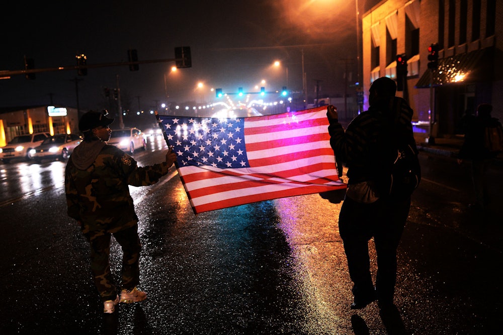 Demonstrators march with an American flag in St. Louis, Missouri, in November 2014 to protest the death of Michael Brown, an unarmed Black teenager who had been shot by police earlier in the year in nearby Ferguson.