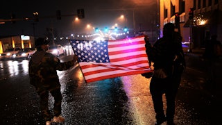 Demonstrators march with an American flag in St. Louis, Missouri, in November 2014 to protest the death of Michael Brown, an unarmed Black teenager who had been shot by police earlier in the year in nearby Ferguson.