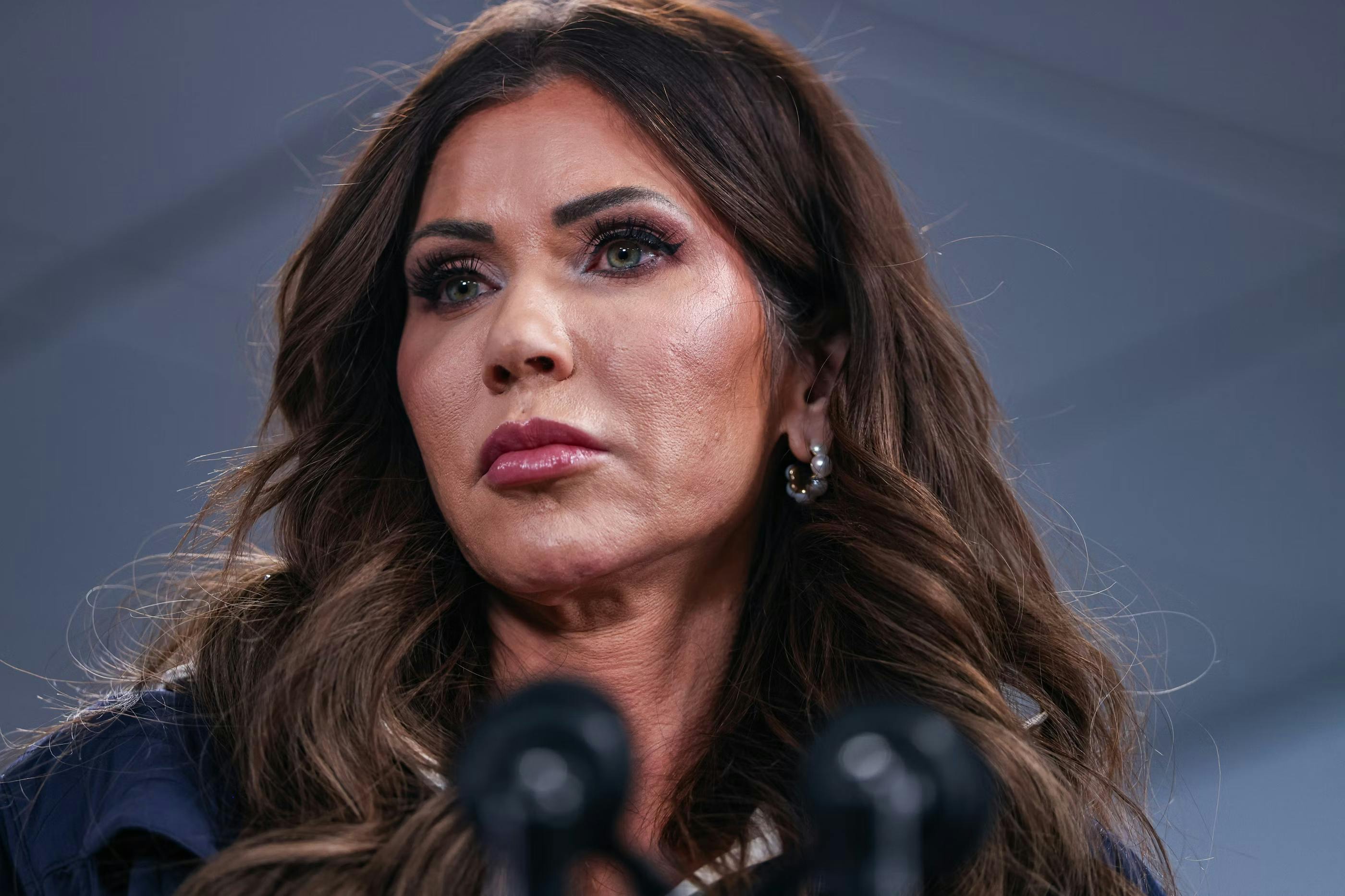 Homeland Secretary Kristi Noem stands at a microphone