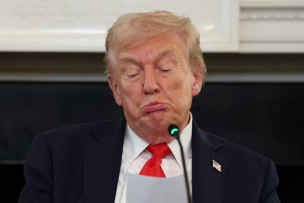 Donald Trump purses his lips and puffs his cheeks out, making a stupid face as he reads from a paper