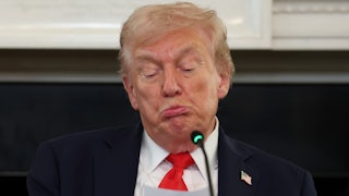 Donald Trump purses his lips and puffs his cheeks out, making a stupid face as he reads from a paper