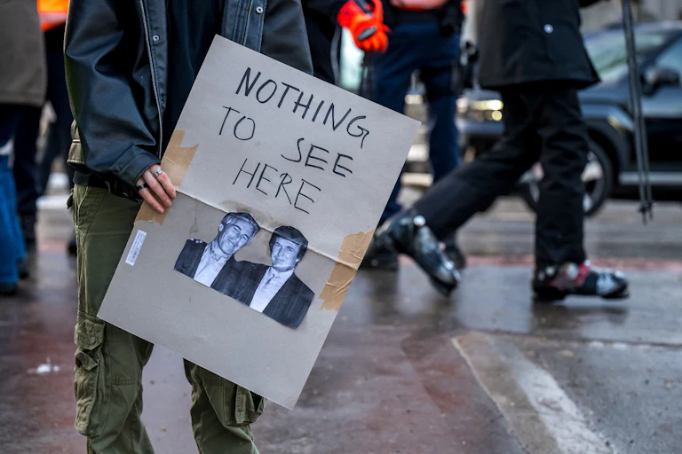 A protester holds a poster with a photo of Jeffrey Epstein and Donald Trump, alongside the words "Nothing To See Here."
