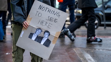 A protester holds a poster with photos of Jeffrey Epstein and Donald Trump, alongside the words "Nothing To See Here."