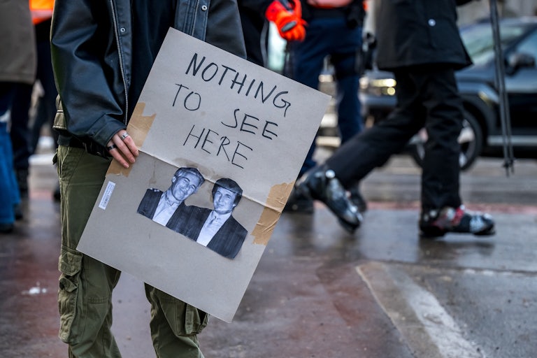 A protester holds a poster with photos of Jeffrey Epstein and Donald Trump, alongside the words "Nothing To See Here."