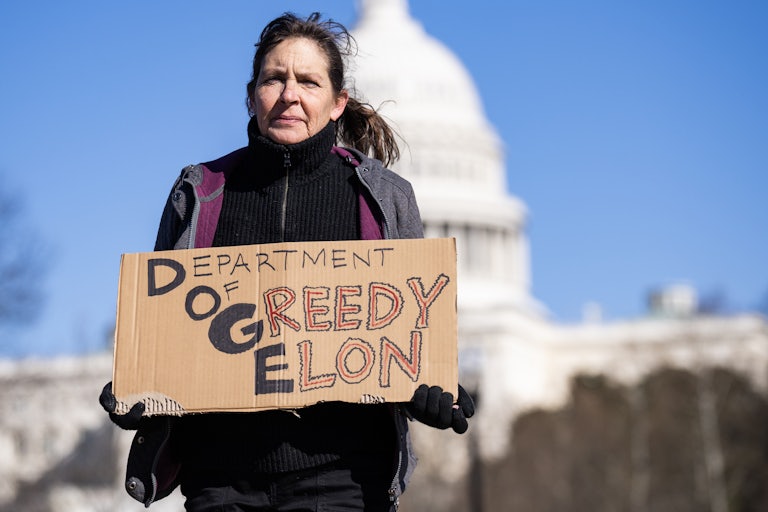 A person holds a sign that says “Department of Greedy Elon” during a protest outside the U.S. Capitol