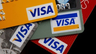 A close-up of four VISA credit cards, stacked in a stylish pile