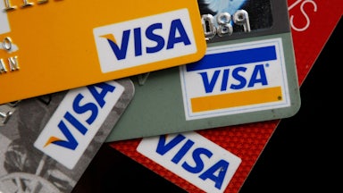A close-up of four VISA credit cards, stacked in a stylish pile