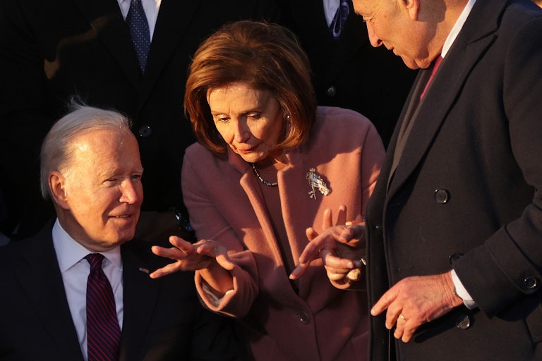 Nancy Pelosi gestures, with Joe Biden seated to the left and Chuck Schumer to the right.