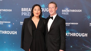 Priscilla Chan and Mark Zuckerberg pose for a picture on a step-and-repeat.