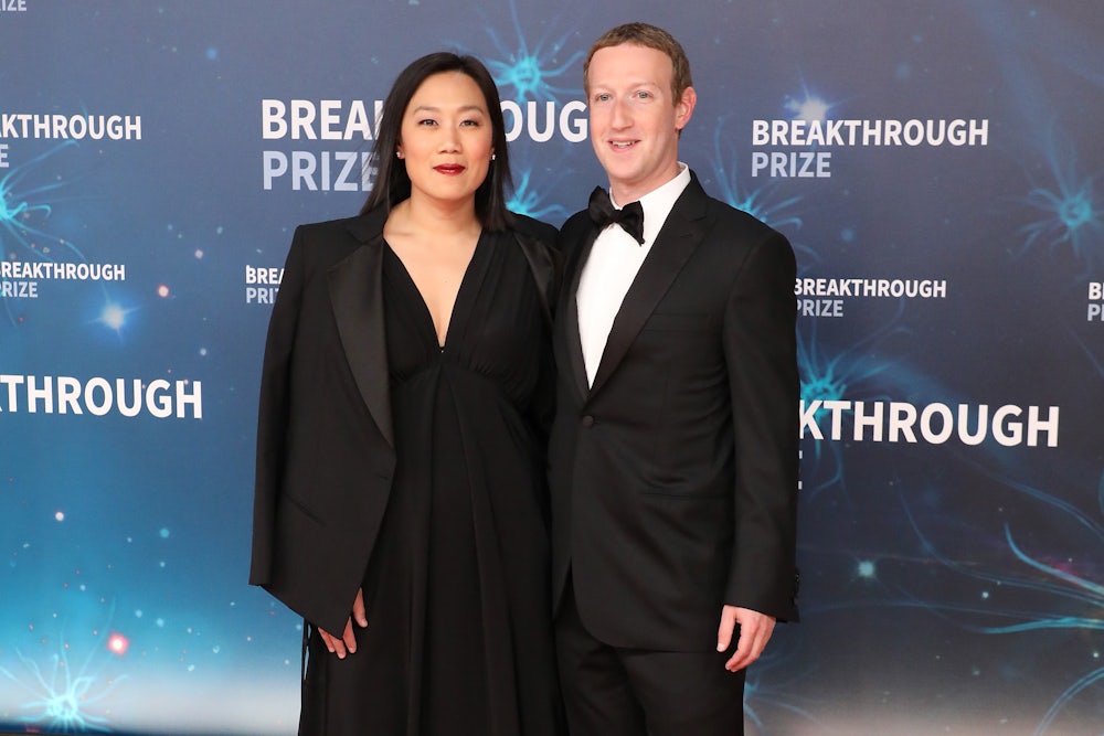 Priscilla Chan and Mark Zuckerberg pose for a picture on a step-and-repeat.