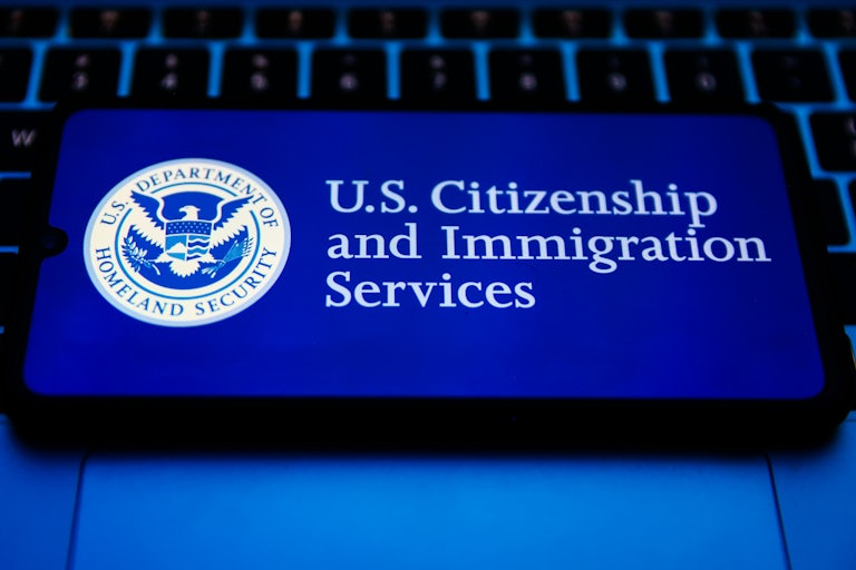 A phone screen shows the logo for U.S. Citizenship and Immigration Services