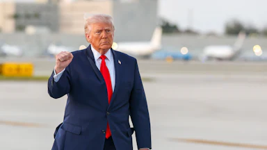 Donald Trump raises a fist while walking on an airport tarmac