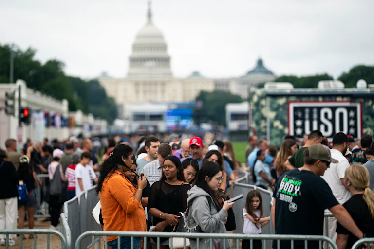 A crowd of people pack the National Mall in front of the Capitol building.