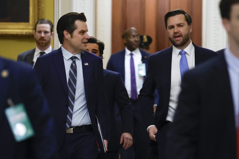 Gaetz and Vance walk down a hallway surrounded by others.