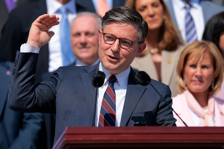 House Speaker Mike Johnson gestures with one hand while speaking at a podium the Capitol steps