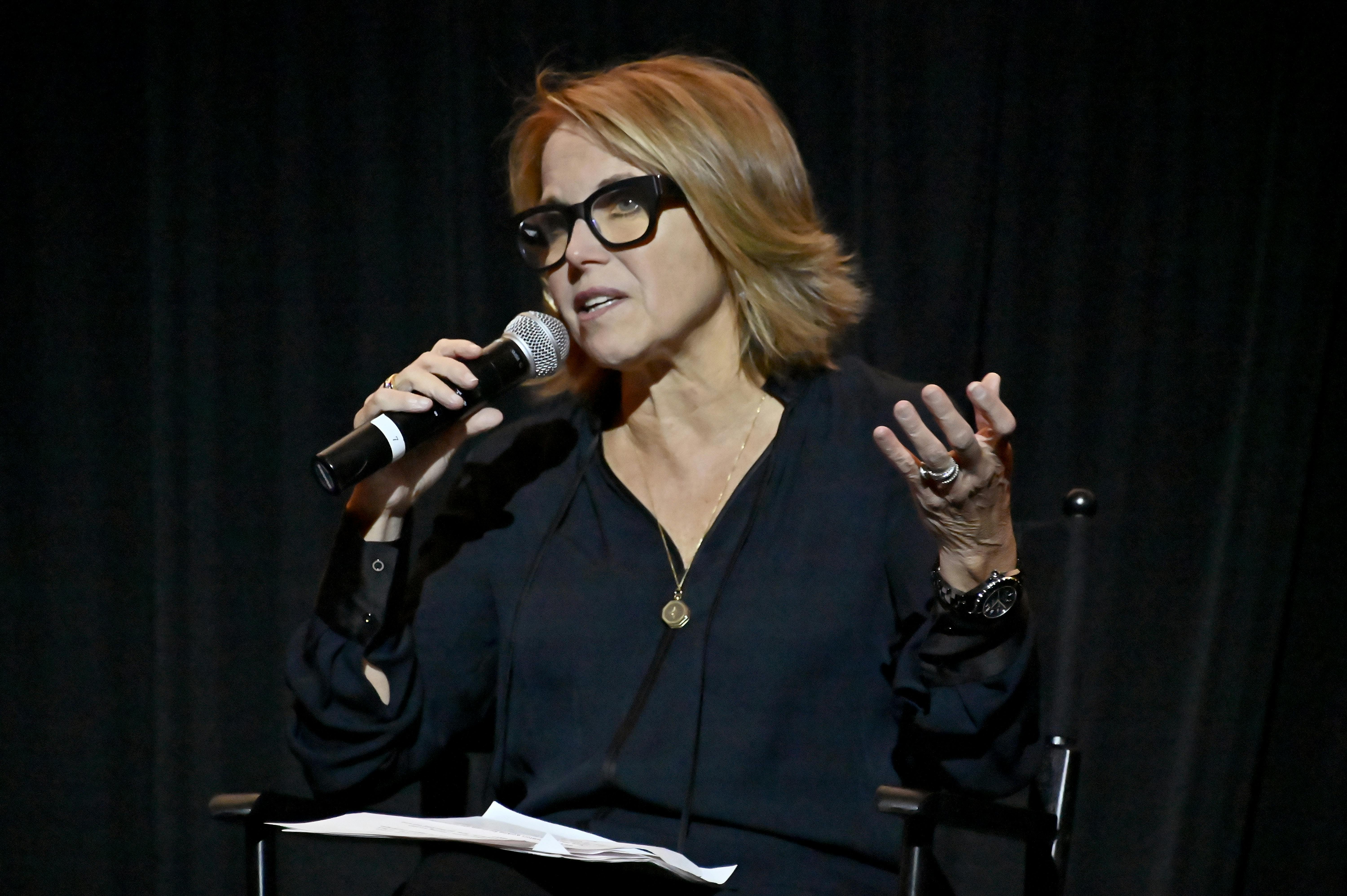 News anchor Katie Couric addresses an audience with a microphone.
