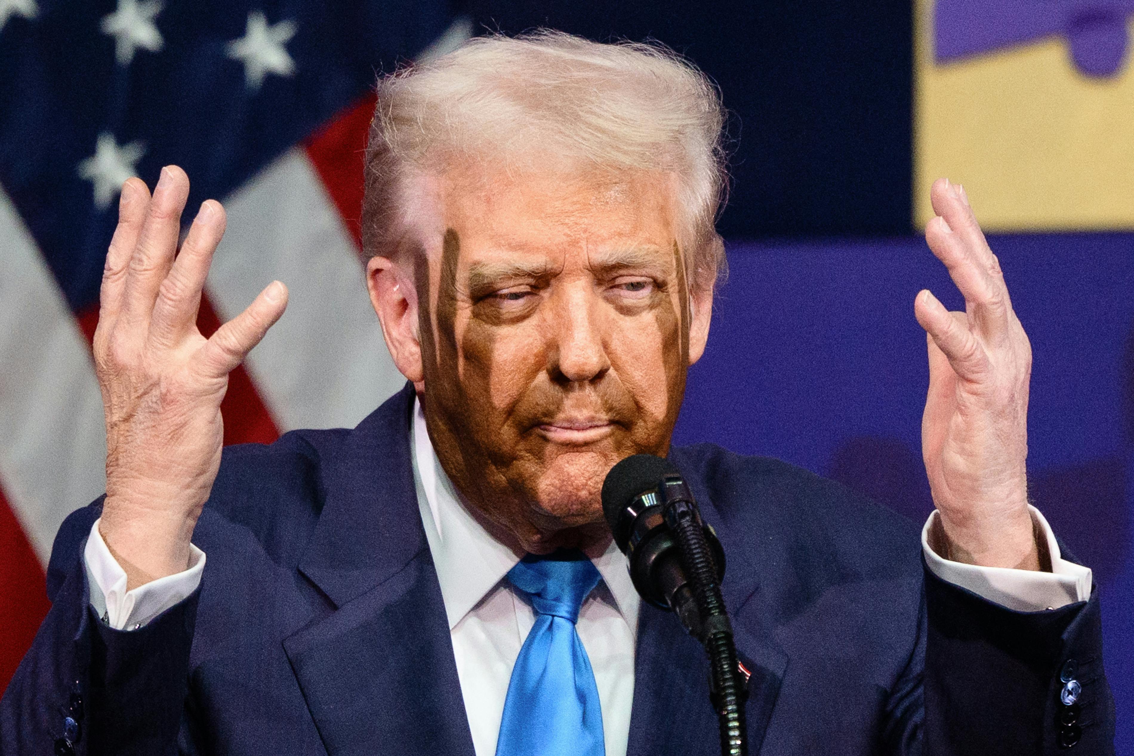 Donald Trump purses his lips and raises his hands next to his face