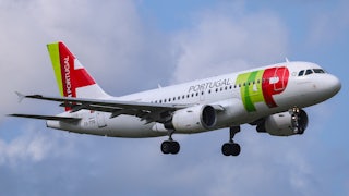 A plane with TAP Air Portugal markings on the side is seen in the air, against a blue sky with clouds.