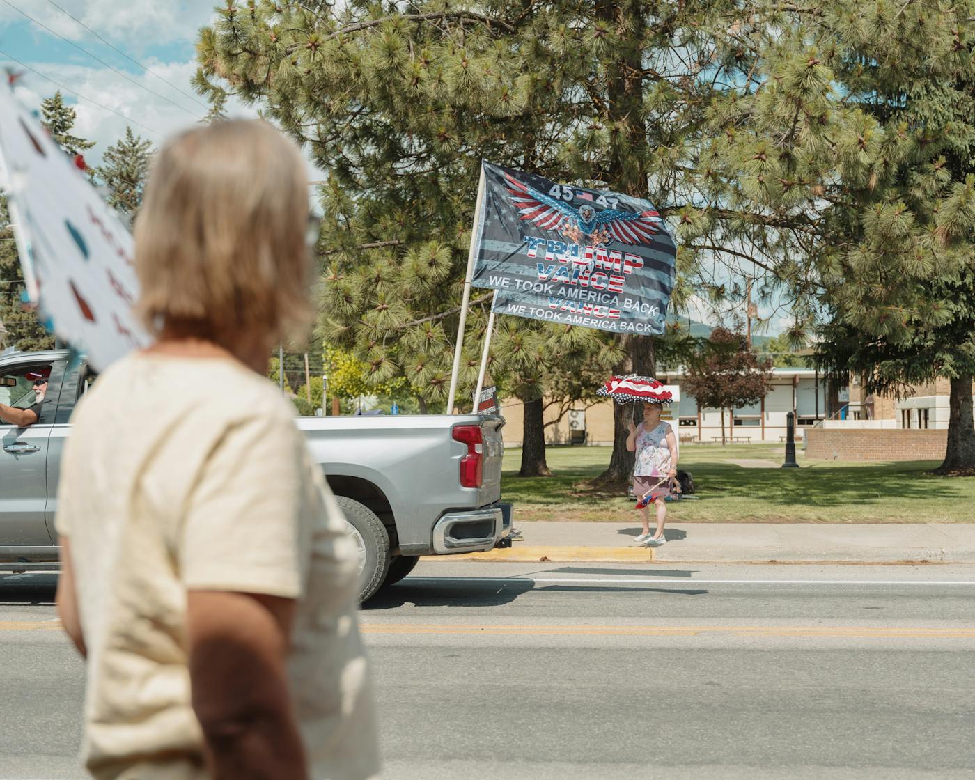 A demonstrator waits to cross the street as a local resident displaying pro-Trump flags on his vehicle drives past the No Kings rally in Libby Montana on June 14