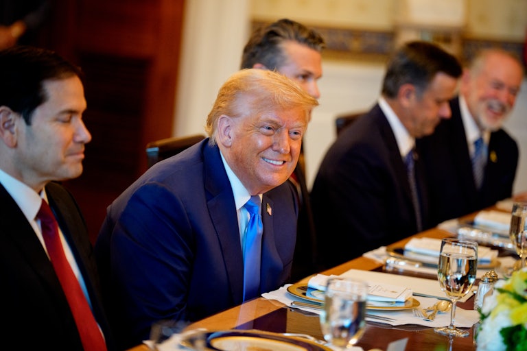 Donald Trump smiles and leans over while seated at a conference table with Secetary of State Marco Rubio, Defense Secretary Pete Hegseth, Central Intelligence Agency Director John Ratcliffe, and U.S. Ambassador to Israel Mike Huckabee.