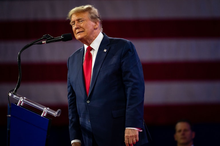 Donald Trump leans towards a microphone