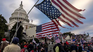 Protesters outside the Capitol on January 6, 2021, with a shredded and upside down U.S. flag in the foreground.