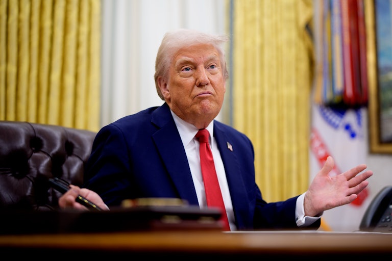 Donald Trump gestures while sitting at his desk in the Oval Office