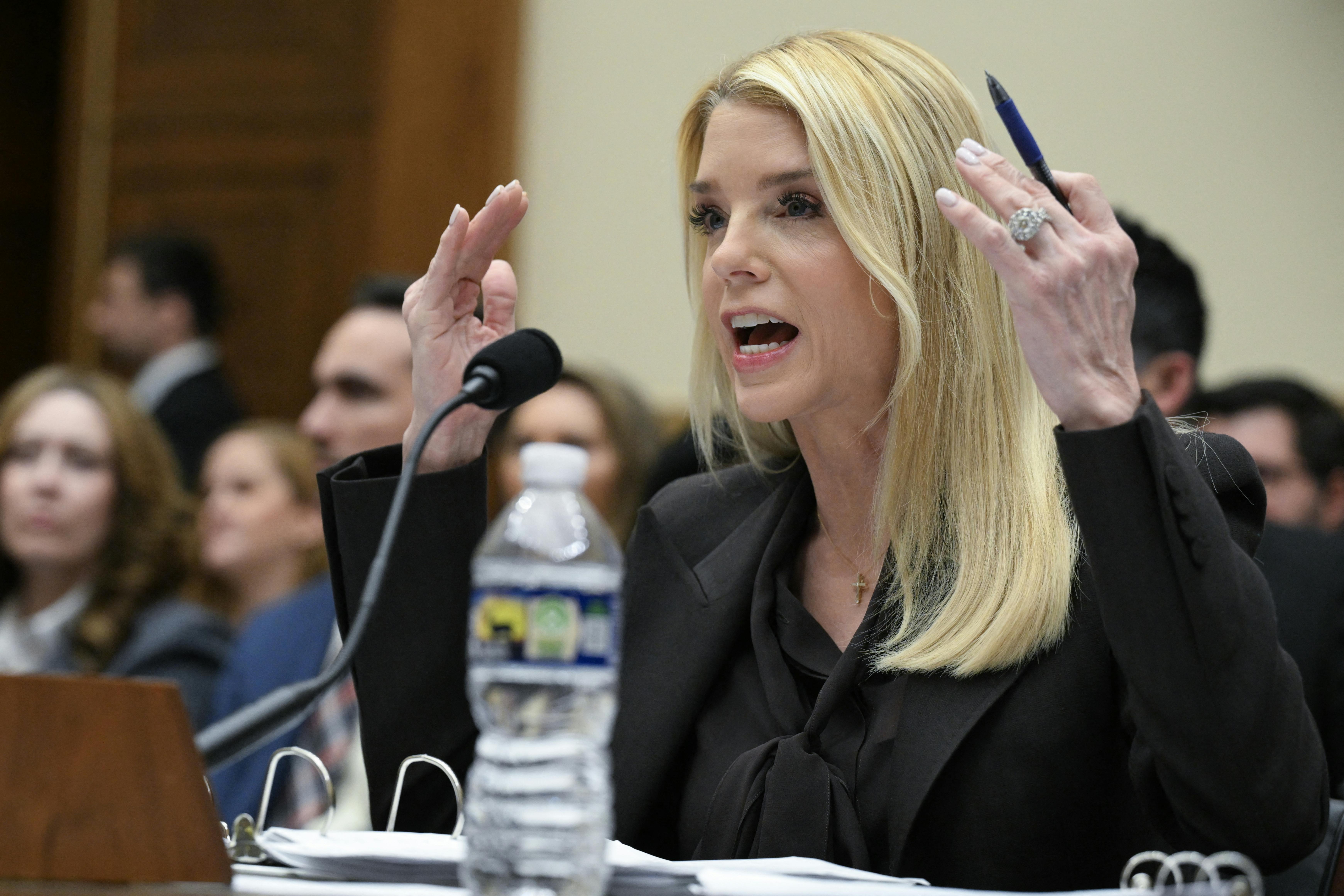 Attorney General Pam Bondi raises her hands in exasperation as she testifies in a House hearing.