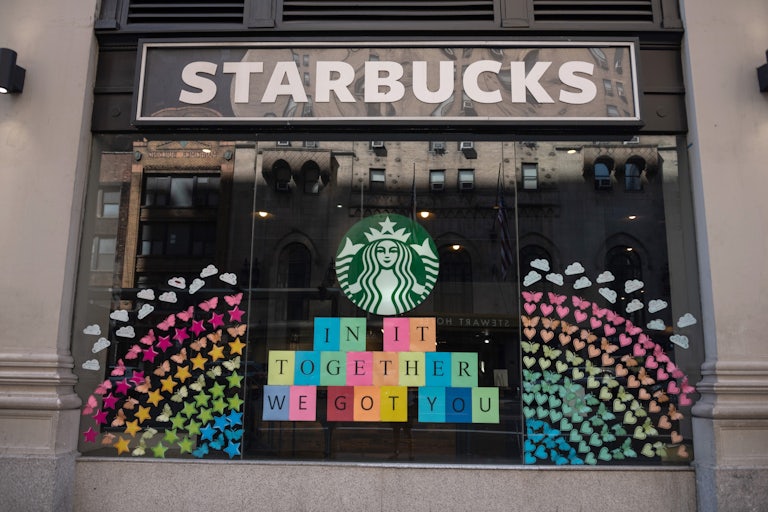 Starbucks storefront has a large rainbow made of hearts, stars, and butterflies, along with a sign that reads: "In it together / we got you"