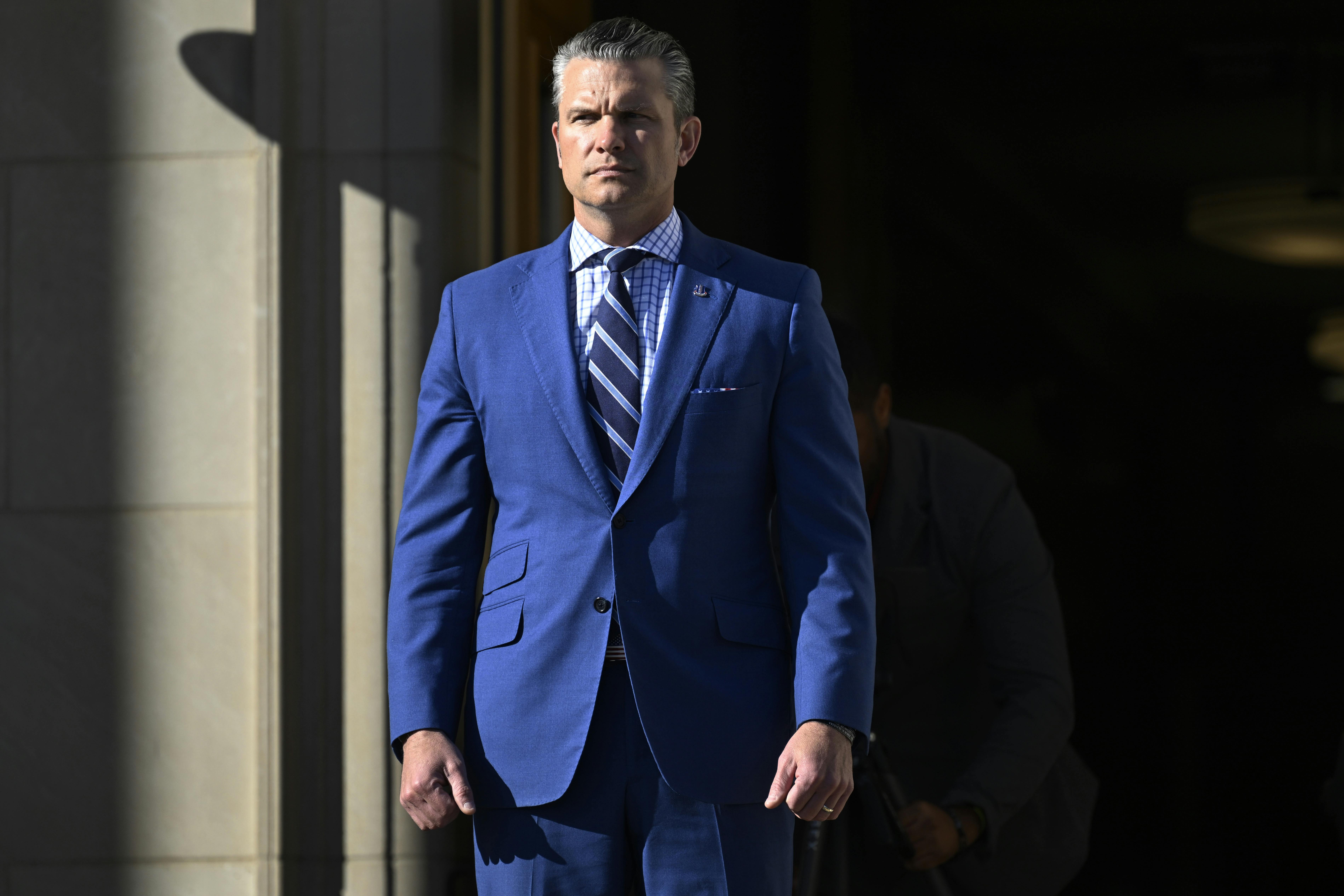 Defense Secretary Pete Hegseth stands at the entrance of the Pentagon