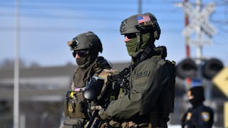 Two masked ICE agents wearing camo (in the snow)