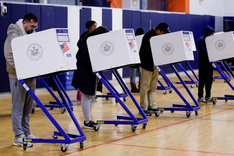 Four voters vote at a polling station.