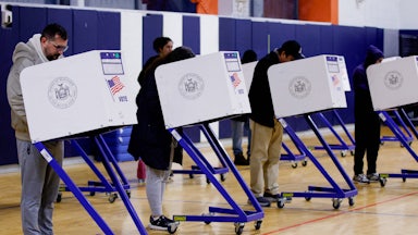 Four voters vote at a polling station.
