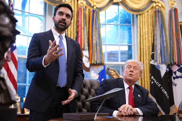 Zohran Mamdani gestures and speaks while standing next to Donald Trump, who sits at his desk in the Oval Office