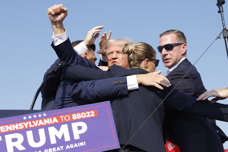 Donald Trump holds up his fist as Secret Service agents rush him off stage after an attempted assassination