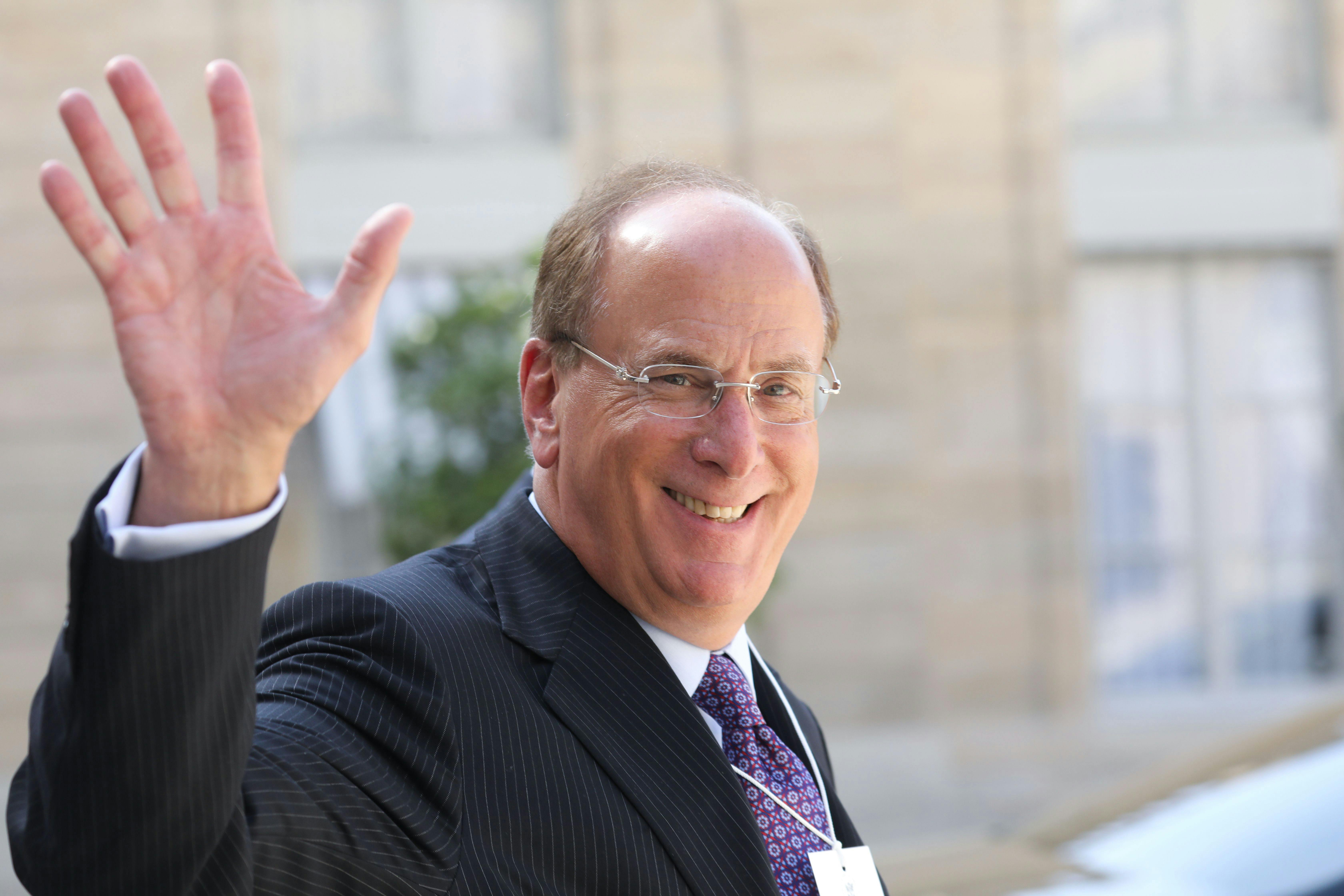 BlackRock CEO Larry Fink smiles and waves.