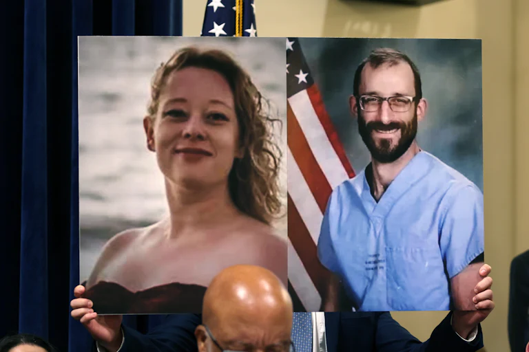 Someone holds up a photo of Renee Nicole Good and Alex Pretti.