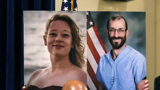 Someone holds up a photo of Renee Nicole Good and Alex Pretti.