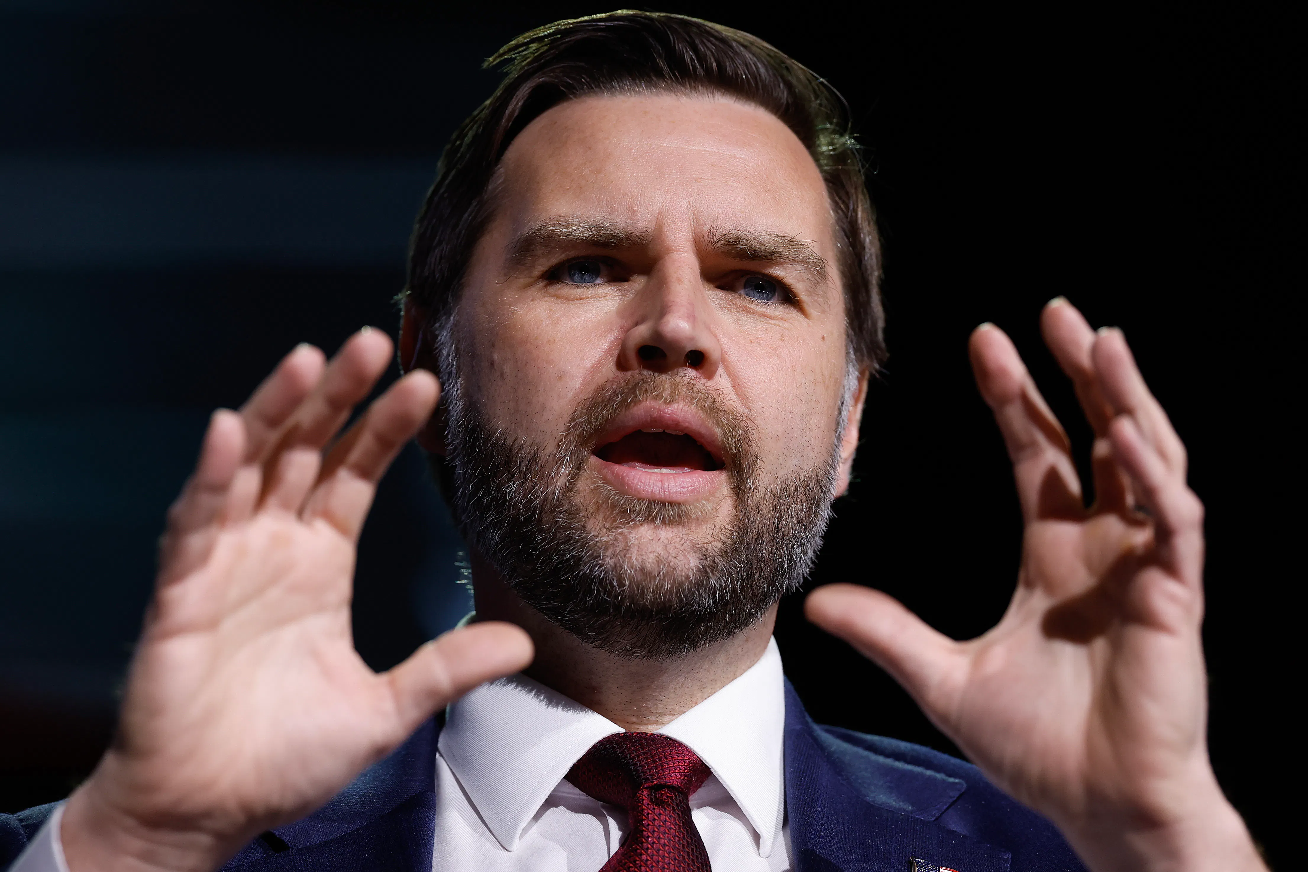 Vice President JD Vance holds up both hands while speaking during a TPUSA event