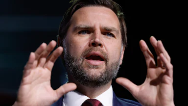 Vice President JD Vance holds up both hands while speaking during a TPUSA event