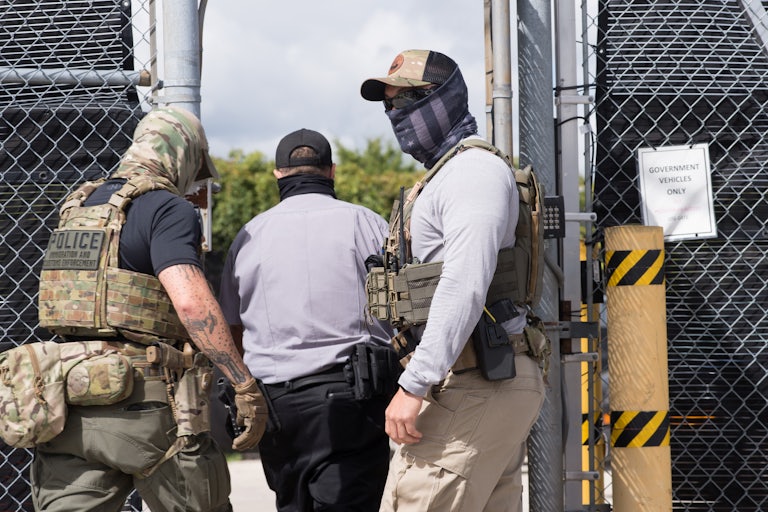ICE officers stand outside of a building.