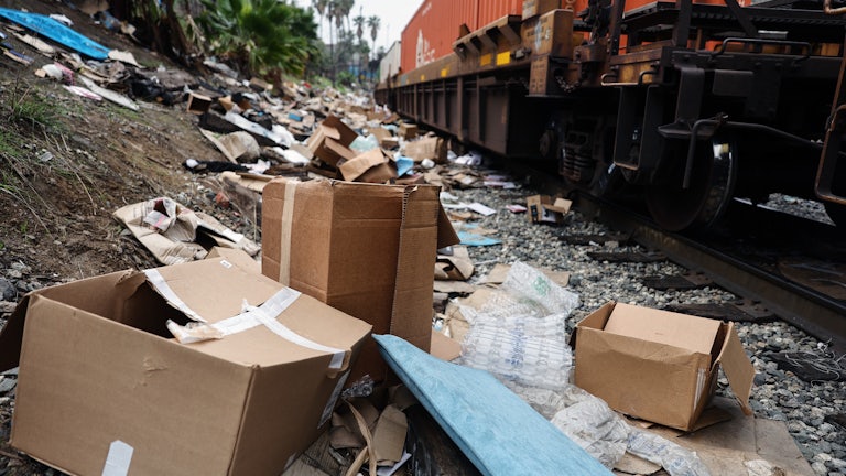 A Union Pacific freight train passes by tracks littered with debris from packages stolen from cargo containers 