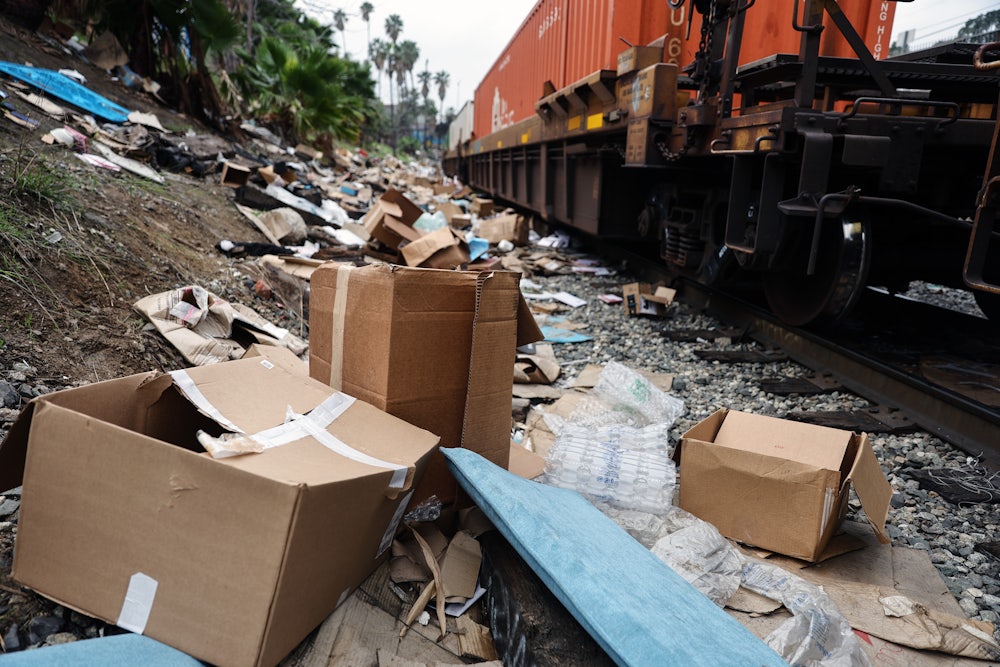 A Union Pacific freight train passes by tracks littered with debris from packages stolen from cargo containers