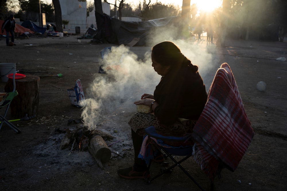 A woman and her husband prepare a fire to cook dinner at Chamizal Park near Bridge of the Americas